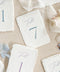 Bring elegance to your reception with our folded handmade paper table numbers. Crafted from luxurious deckled-edge cotton paper, each card features modern calligraphy paired with soft, timeless colors to guide guests effortlessly. Their folded construction allows them to stand on their own, creating a refined and cohesive tablescape for weddings, celebrations, and fine-art events.
