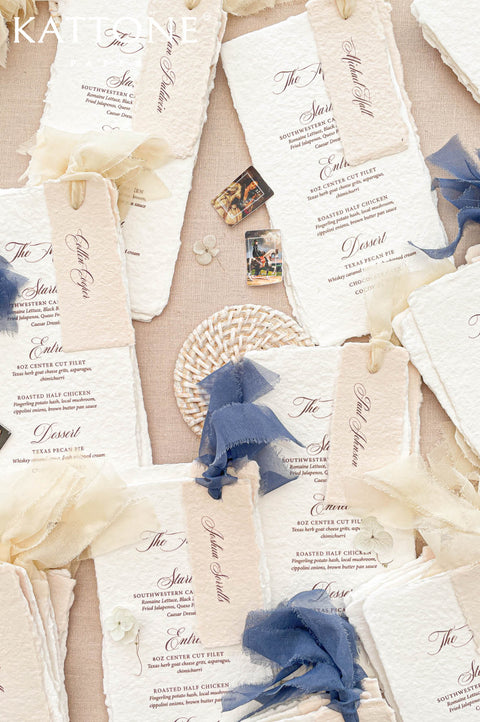 Luxury handmade paper wedding menus featuring deckled edge cotton paper, personalized guest name tags, elegant typography, and chiffon ribbon styling.