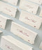 Elevate your table setting with our folded handmade paper place cards, crafted from luxurious deckled-edge cotton paper. Each card features elegant script printing and a petite icon detail, creating a timeless and refined look for weddings, events, and intimate gatherings. Their folded design allows them to stand beautifully on any tablescape, adding effortless sophistication.
