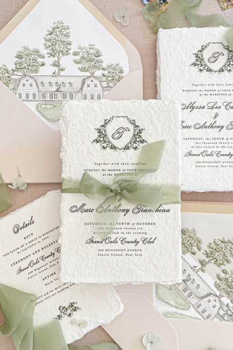 Luxury handmade paper wedding invitation suite with sage chiffon ribbon, botanical crest monogram and blush envelopes with custom venue illustration liners.
