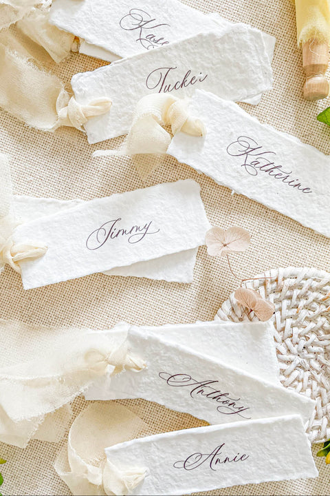 Add a touch of effortless elegance to your event with our handmade paper place cards, featuring natural deckled edges, soft ivory chiffon ribbon, and refined calligraphy. Each card is delicately crafted to elevate your wedding tablescape with a romantic, airy, and organic aesthetic. Perfect for fine-art weddings, garden celebrations, and timeless event styling.