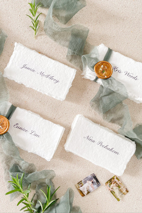 Enhance your tablescape with our handmade paper place cards, crafted from luxurious cotton rag paper and finished with naturally torn deckled edges. Each card features elegant calligraphy, soft hand-dyed ribbon, and the option of a wax seal for added fine-art charm. Perfect for weddings, engagement parties, showers, and upscale events, these artisanal place cards bring texture, romance, and sophistication to every setting.