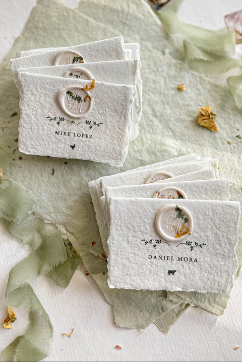 Elevate your table setting with our fine-art handmade paper place cards, each adorned with an elegant pressed-flower wax seal and delicate botanical artwork. Crafted from luxury deckled-edge cotton paper, these name cards bring a romantic, organic charm to weddings, garden celebrations, and intimate events. Their soft sage tones and artisanal texture create an unforgettable, heirloom-quality detail for your guests.