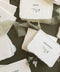 Handmade wedding place cards with deckled edges, botanical greenery illustration and elegant serif names on cotton paper.