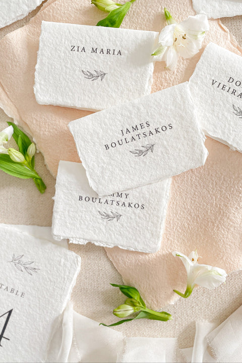 Elevate your event with our handmade paper place cards, crafted from luxurious cotton rag paper and finished with naturally torn deckled edges. Each card features minimalist typography paired with a delicate botanical illustration, creating a refined fine-art look perfect for weddings, rehearsal dinners, and intimate celebrations. These artisan-crafted place cards bring organic texture, timeless elegance, and a soft romantic touch to any tablescape.
