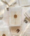 This handmade paper wedding invitation suite combines fine craftsmanship with opulent detailing. Printed on luxury cotton paper with deckled edges, each invitation is accented with subtle touches of gold leaf, catching the light with a refined shimmer that speaks of romance and sophistication. The design features a hand-painted floral monogram, symbolizing the couple’s union, surrounded by soft watercolor greenery and pastel hues.