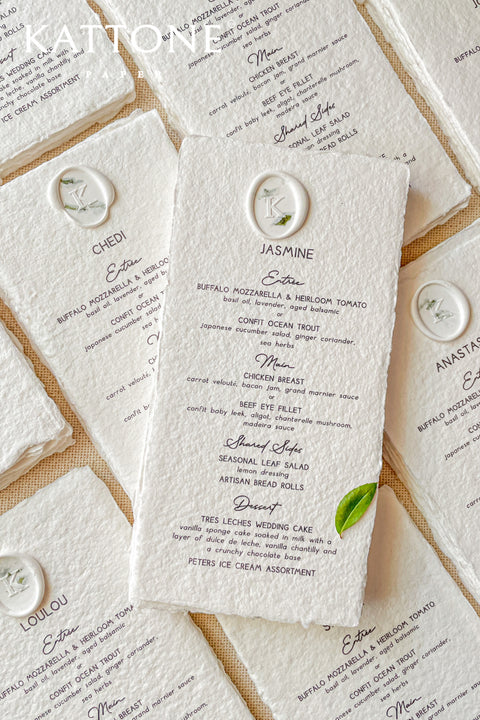 Elevate your tablescape with these luxurious handmade paper menus, beautifully crafted from 100% cotton rag paper and finished with natural deckled edges for an artisanal touch. Each menu is printed with elegant typography and adorned with a refined wax seal, personalized with your monogram or crest, adding a timeless and sophisticated detail to your event design.