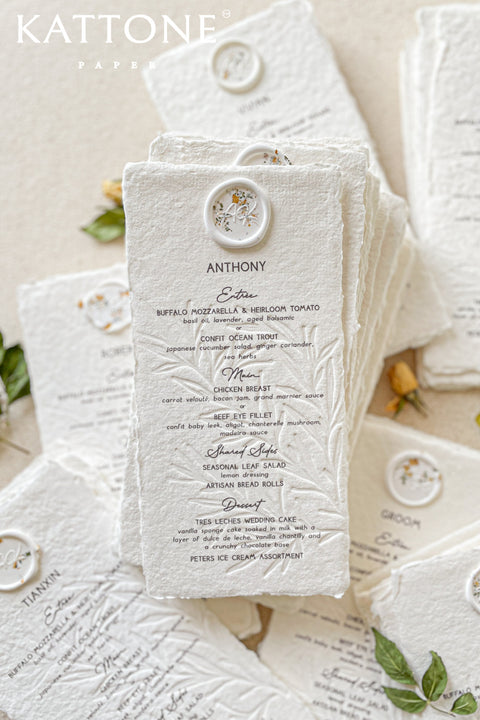 Elevate your wedding table with our embossed handmade paper menus, where timeless craftsmanship meets modern refinement. Each menu is printed on 100% cotton handmade paper with delicate deckled edges and a subtle botanical embossing, creating a tactile experience of understated luxury. Finished with an elegant floral wax seal personalized for each guest, these menus add an exquisite fine-art touch to your reception decor.