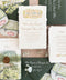 Luxury handmade paper wedding invitation suite featuring deckled edge cotton paper, custom watercolor venue illustration, scenic vellum wrap, sage green envelopes with white ink addressing, and coordinated watercolor stationery details.