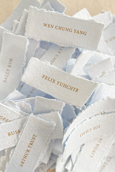 Bring refined elegance to your event with our colored handmade paper place cards, crafted from luxurious cotton rag paper and finished with naturally torn deckled edges. Each card is printed with crisp, minimalist lettering in a warm metallic tone - perfect for weddings, rehearsal dinners, corporate events, or fine-art celebrations. Their soft, muted shades add depth, texture, and a sophisticated touch to any tablescape.