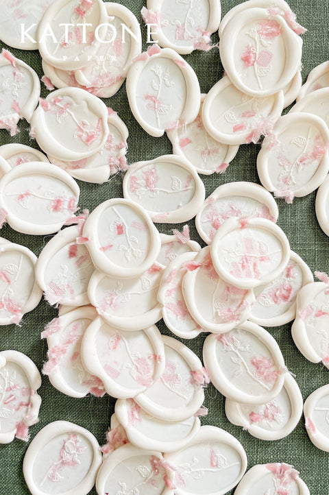 Handmade floral wax seals with ivory wax and soft pink botanical accents for wedding stationery.