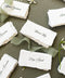 Handmade paper wedding place cards with deckled edges and calligraphy names on a neutral linen background.