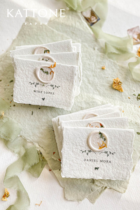 Elevate your table setting with our fine-art handmade paper place cards, each adorned with an elegant pressed-flower wax seal and delicate botanical artwork. Crafted from luxury deckled-edge cotton paper, these name cards bring a romantic, organic charm to weddings, garden celebrations, and intimate events. Their soft sage tones and artisanal texture create an unforgettable, heirloom-quality detail for your guests.