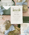 Luxury handmade paper wedding invitation suite featuring deckled edge cotton paper, custom venue sketch illustration, scenic vellum wraps, sage green envelopes, and powder blue chiffon ribbon styling.