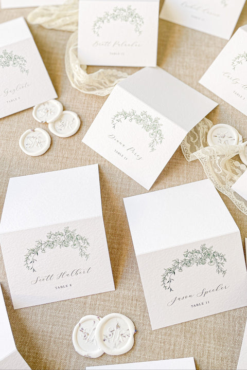 Elevate your wedding seating display with our place cards, designed on premium textured cardstock and adorned with a delicate greenery arch illustration. Their timeless botanical style blends perfectly with garden weddings, fine-art celebrations, and romantic outdoor events. These folded cards stand beautifully on tables, adding elegance, clarity, and natural charm to every setting.