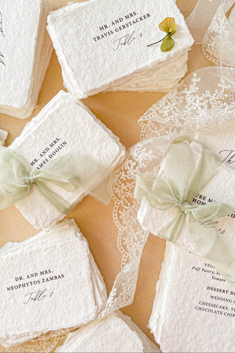 Add refined, old-world elegance to your event with our handmade paper place cards, crafted from luxurious cotton rag paper and finished with naturally torn deckled edges. Each card features elegant serif typography and optional soft green ribbon, creating a timeless fine-art aesthetic perfect for weddings, rehearsal dinners, and sophisticated celebrations. Their artisanal texture, organic silhouette, and customizable details bring beauty and authenticity to every tablescape.