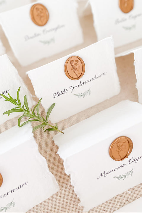 Elevate your wedding or event with our handmade paper place cards, crafted from luxurious cotton rag paper and finished with naturally torn deckled edges. Each card is adorned with a warm copper wax seal and elegant calligraphy, creating a timeless, fine-art detail that enhances any tablescape. Designed to bring organic texture, charm, and sophistication, these artisan place cards make your seating display unforgettable.