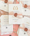 Handmade paper wedding invitations with custom monogram crest, blush silk ribbon, wax seal detail, and deckle edge cotton paper.