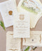 Handmade paper wedding invitation with deckled edges, gold crest monogram, luxury wax seal, fine art wedding stationery flat lay.
