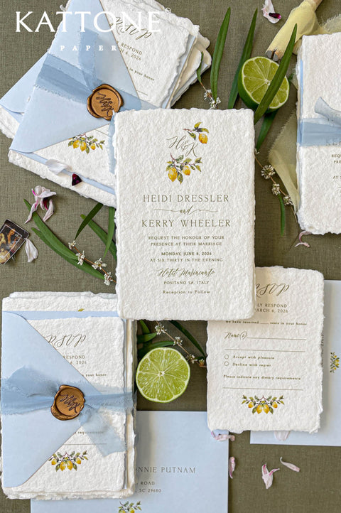 Handmade paper wedding invitation suite with deckle edges, custom watercolor lemon illustrations, soft blue envelopes, and wax seal accents.