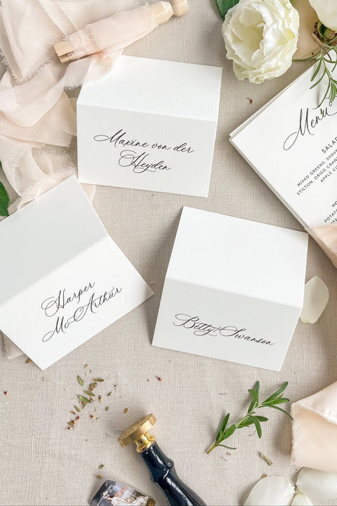 Elevate your event with our refined place cards, crafted from premium cardstock and designed with elegant handwritten-style calligraphy. Their crisp, minimalist look makes them perfect for weddings, rehearsal dinners, galas, and sophisticated gatherings. With a clean folded silhouette and timeless aesthetic, these place cards bring effortless beauty, clarity, and polished charm to any seating display.