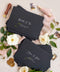 Matte black wedding envelopes with white ink address printing, styled flat lay with florals, wax seal, and greenery, perfect for modern and editorial invitation suites.