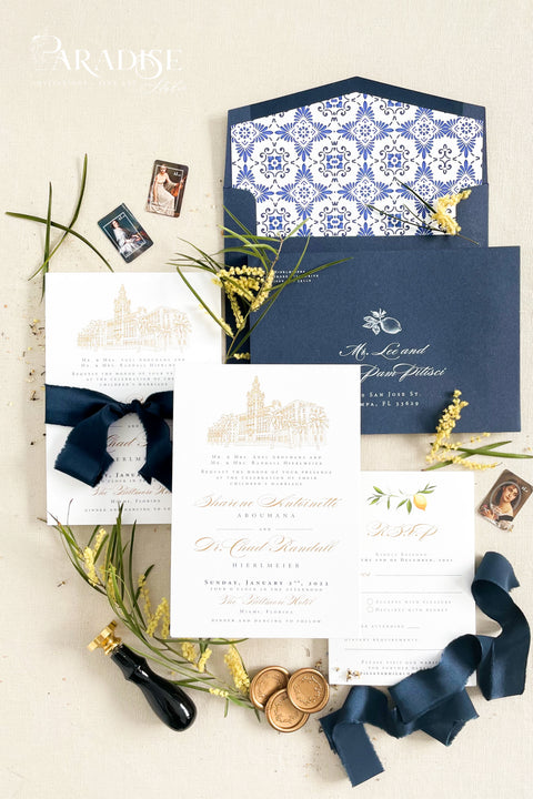 Inspired by the golden light and charm of European summers, this wedding invitation suite combines custom hand-drawn architecture with delicate watercolor lemons for a design that’s both luxurious and full of life. The venue illustration is created by hand, transforming your wedding location into a piece of art that sets the tone for your day. Paired with rich navy envelopes, an ornate blue patterned liner, and velvet ribbon accents, the result is a suite that exudes elegance and personality.