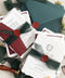 This handmade wedding invitation suite captures the essence of fine art stationery with a touch of deep, moody charm. Printed on luxury cotton paper with natural deckled edges. The suite is adorned with your custom monogram - hand-drawn to reflect your initials and personal style - and wrapped in a forest green silk ribbon with a red wax seal for a dramatic yet refined finish. Paired with rich burgundy backing cards and green envelopes.