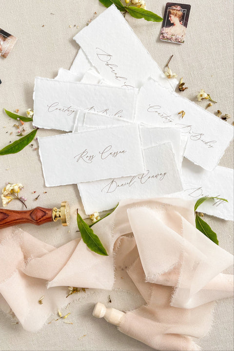 Create a timeless, romantic tablescape with our handmade paper place cards, crafted from luxurious cotton rag paper and finished with natural deckled edges. Each piece features elegant handwritten calligraphy and a soft fine-art texture that complements weddings, intimate dinners, bridal showers, and elevated celebrations. Their artisanal character and organic feel bring warmth, refinement, and delicate charm to any event setting.