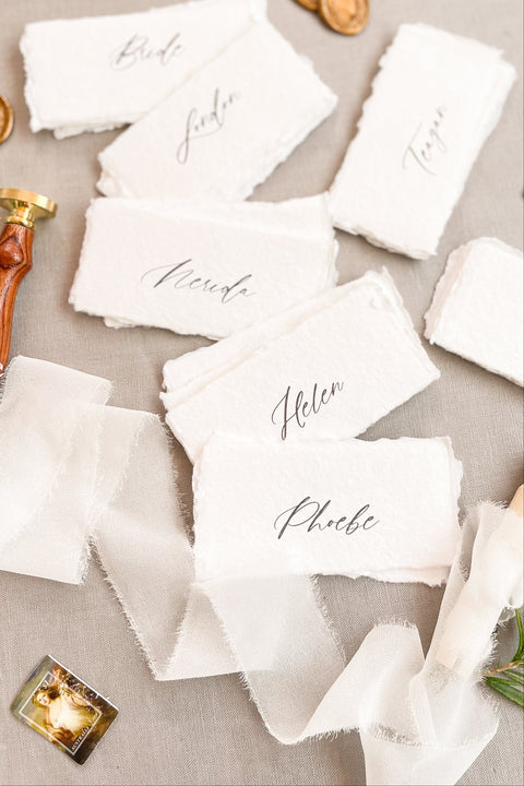Elevate your tablescape with our handmade paper place cards, crafted from luxurious cotton rag paper and finished with naturally torn deckled edges. Each card features elegant modern calligraphy and a soft fine-art texture, making them the perfect addition to weddings, intimate dinners, bridal showers, or elevated celebrations. These artisan-made cards bring timeless beauty, organic character, and refined simplicity to any event setting.