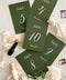 These deep green table numbers bring an elevated, nature-inspired touch to your wedding décor. Designed with crisp white lettering and subtle botanical illustrations, they strike the perfect balance between modern simplicity and organic charm. Printed on luxurious heavyweight cardstock, each piece adds depth, contrast, and effortless sophistication to any tablescape, whether your celebration leans rustic, elegant, or garden-inspired.