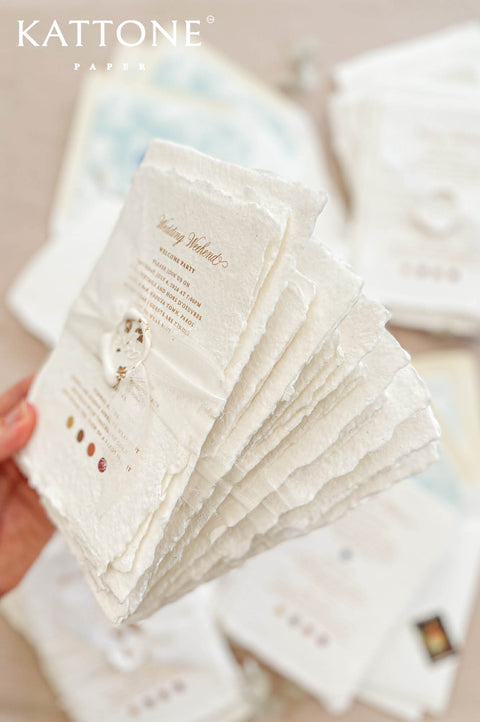 Handmade cotton paper with visible fibers and organically torn deckled edges creating a soft artisanal texture.