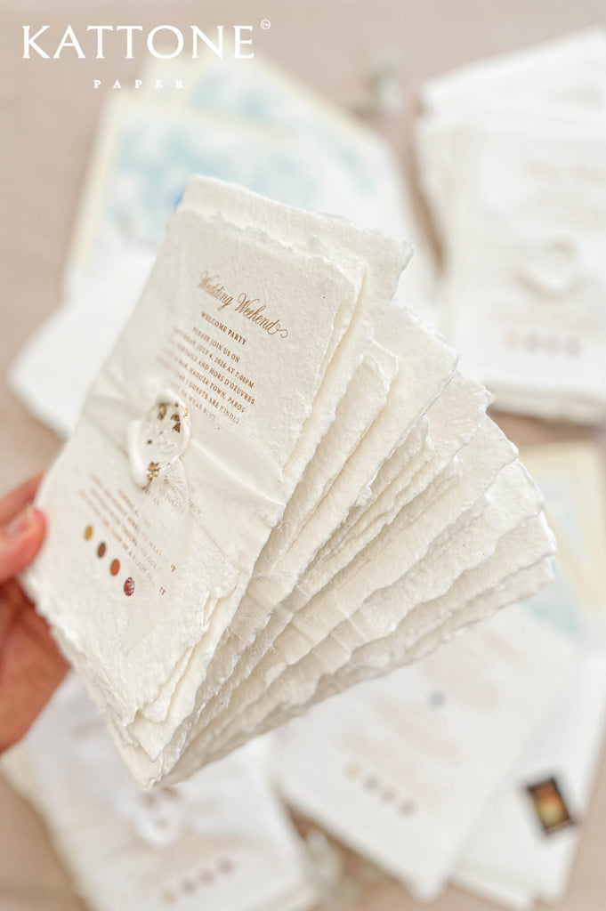 Handmade cotton paper with visible fibers and organically torn deckled edges creating a soft artisanal texture.