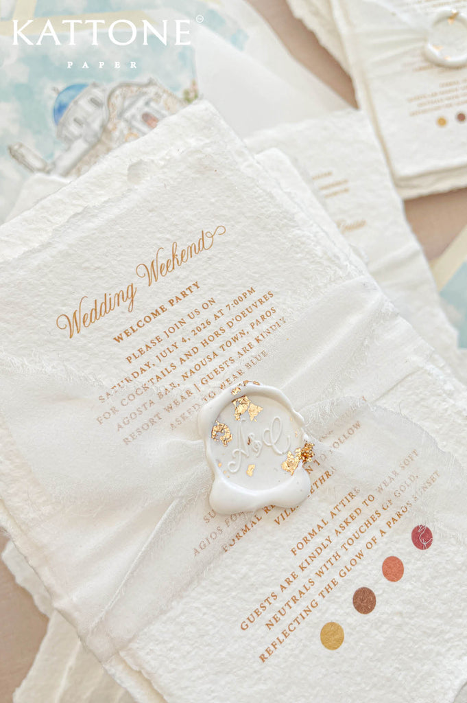 Close up of handmade cotton paper invitation highlighting textured deckled edges, elegant gold typography and soft artisanal paper surface.