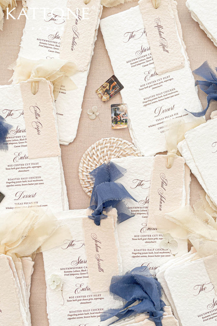 Luxury handmade paper wedding menus featuring deckled edge cotton paper, personalized guest name tags, elegant typography, and chiffon ribbon styling.