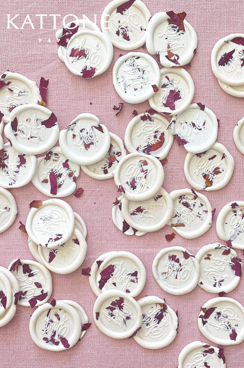 Handmade wax seals with custom monogram and pressed rose petals, luxury wedding stationery detail.