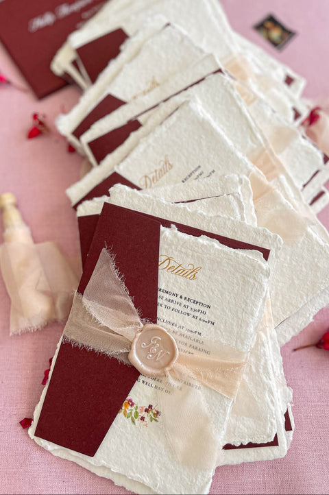 Stacked handmade paper wedding invitations showcasing organic deckle edges and artisanal paper texture.