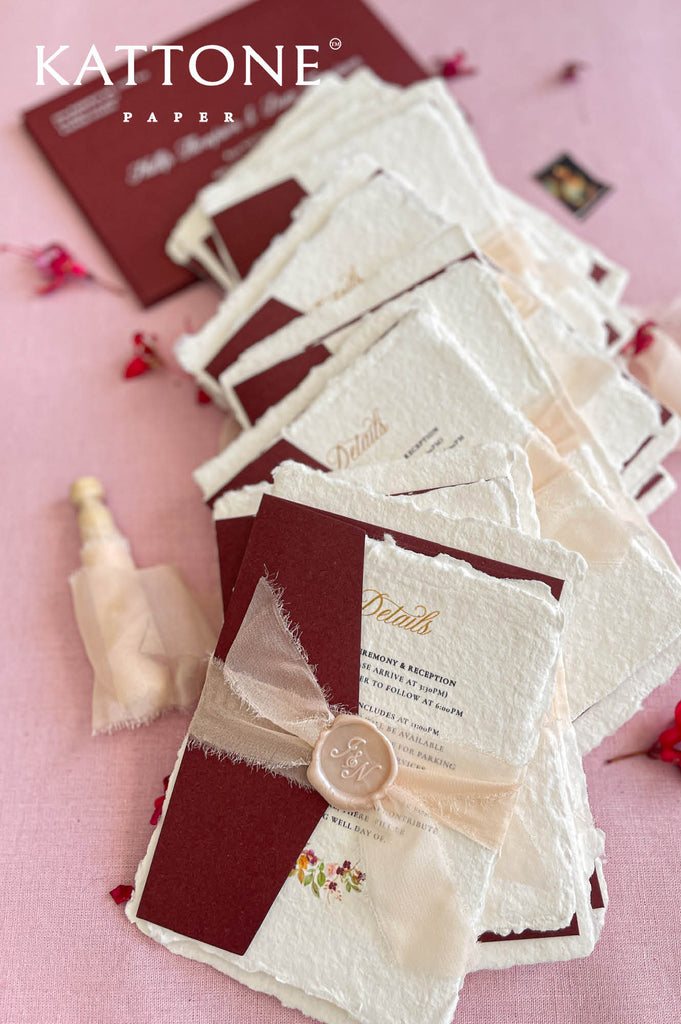 Stacked handmade paper wedding invitations showcasing organic deckle edges and artisanal paper texture.