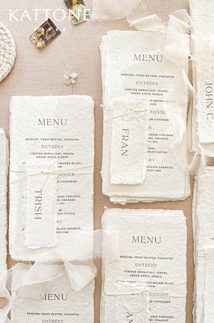 Luxury handmade paper wedding menus featuring deckled edge cotton paper, personalized handmade place cards, minimalist typography, and soft ivory chiffon ribbon styling.