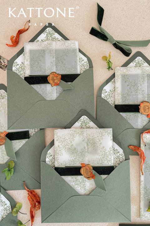 Overlapping soft green envelopes revealing watercolor floral liners, emphasizing muted tones and elegant botanical illustration.