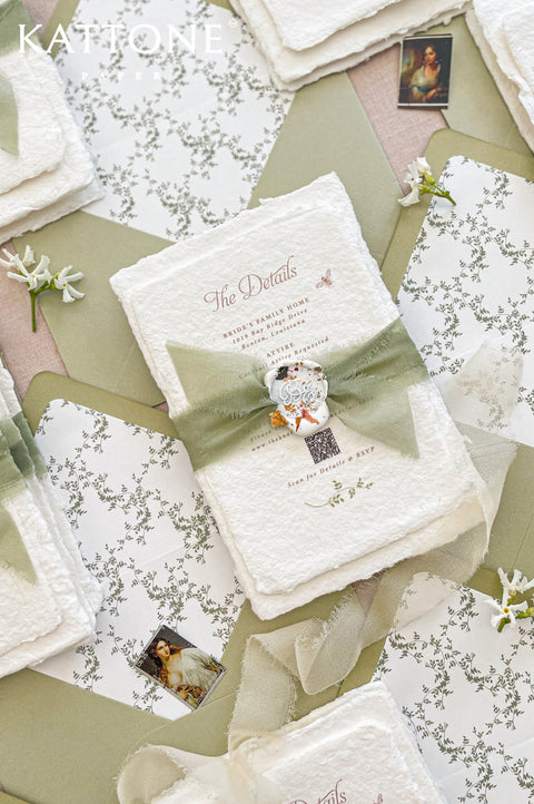Fine art wedding invitation suite styled with handmade paper invitations, sage ribbon, botanical liners and coordinated envelopes.