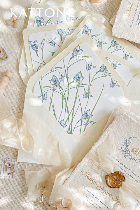Close-up of watercolor floral envelope liner inside ivory envelope showing delicate blue florals and smooth premium paper texture.