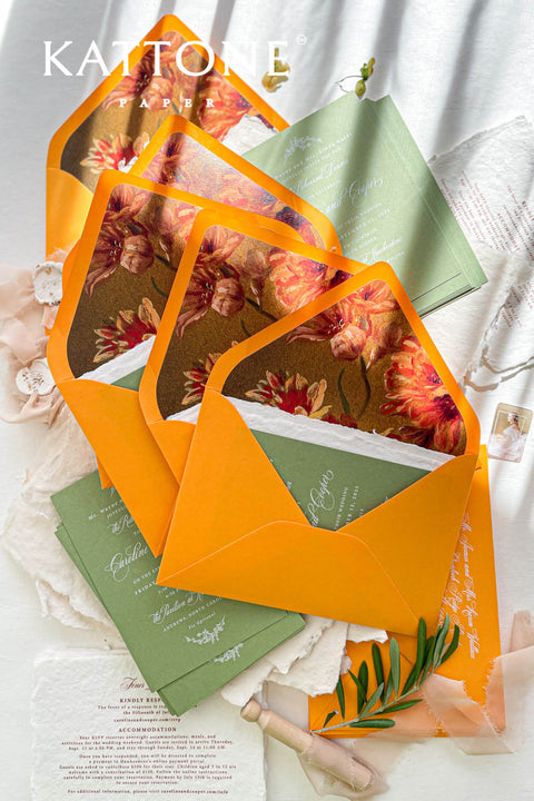 Terracotta wedding envelopes with floral envelope liners styled with handmade paper, greenery, and fine art wedding stationery details.