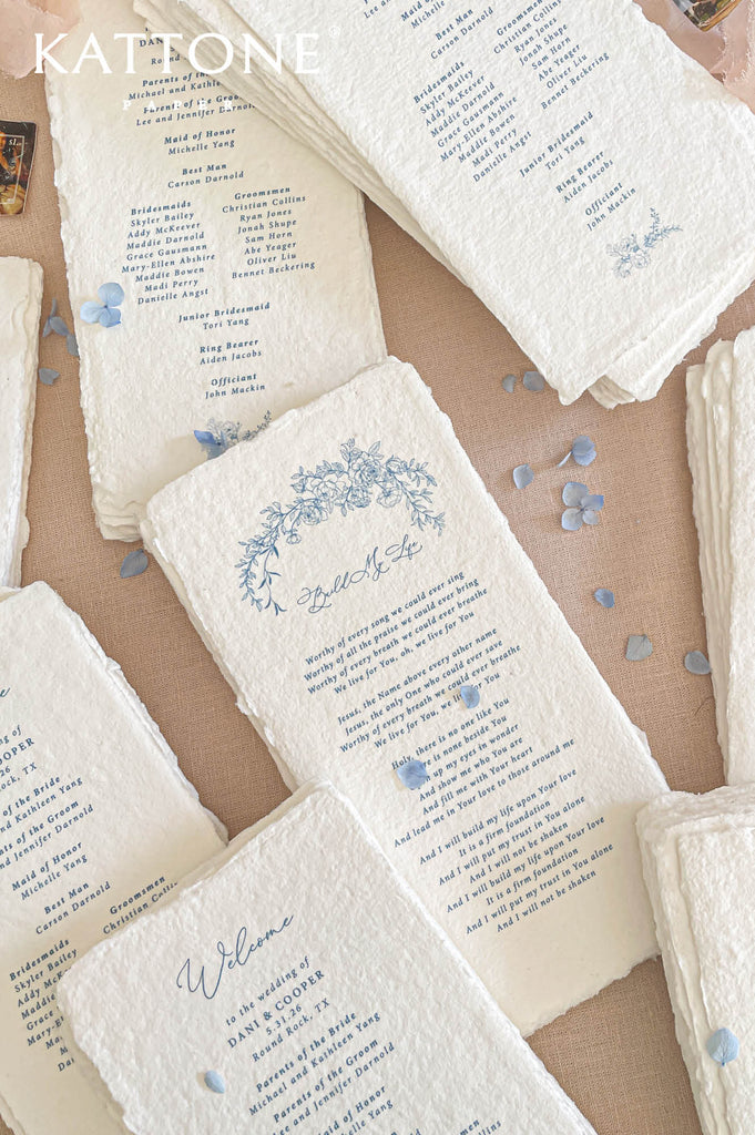 Elegant handmade paper wedding program with deckled edges designed with ceremony details, wedding party information, and floral illustrations.