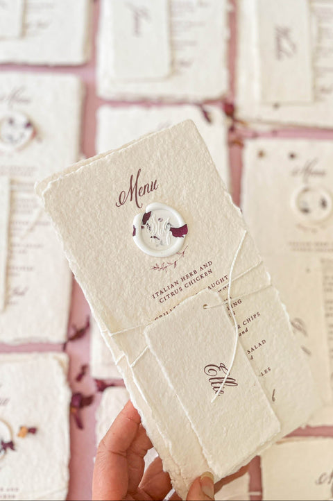 Close-up of handmade paper wedding menu with matching place name tag and elegant calligraphy typography.