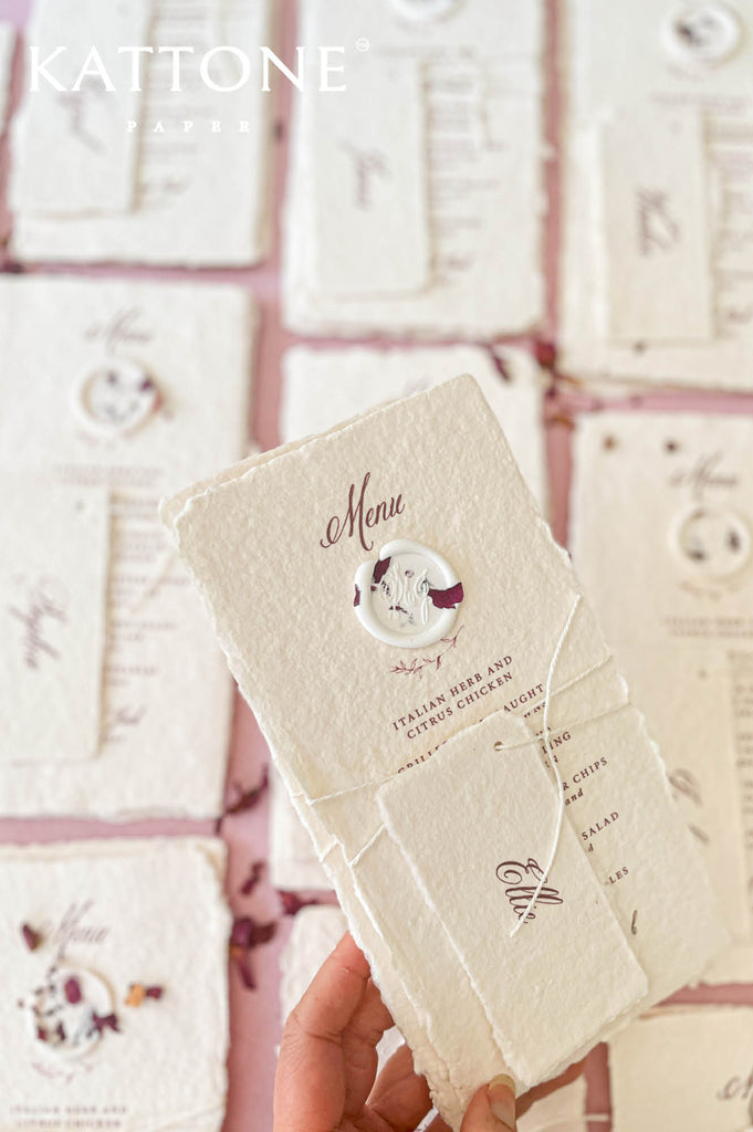 Close-up of handmade paper wedding menu with matching place name tag and elegant calligraphy typography.
