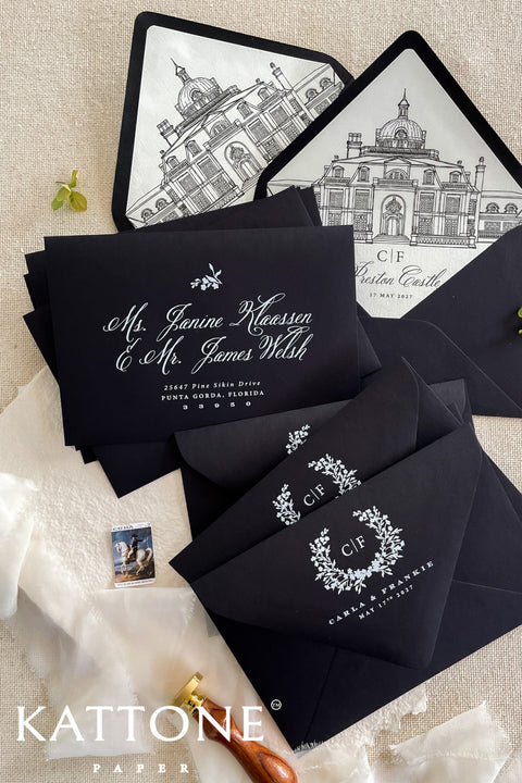 Stack of black envelopes with white ink printing and illustrated venue liners visible, highlighting premium paper quality and craftsmanship.