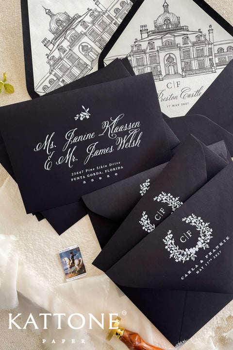 Black wedding envelopes with white ink address printing and hand-drawn venue liners styled with fine art stationery and neutral flat lay details.