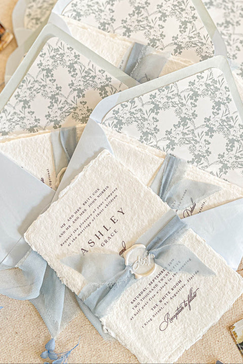 Collection of wedding invitations and stationery items, assembled with silk ribbons and wax seals. envelope liners. Elevate your special day with our Briseis Handmade Paper Wedding Invites. Crafted with love and attention to detail, these elegant invitations blend rustic charm with modern design. Each piece is made from eco-friendly materials, ensuring a unique touch for your celebration. Perfect for intimate gatherings or grand affairs, our invites set the tone for your wedding. 