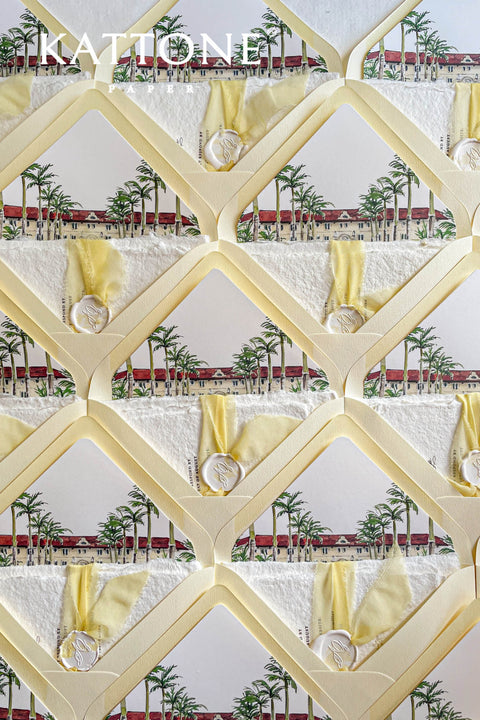 Overlapping soft yellow envelopes revealing watercolor venue liners, emphasizing pastel tones and elegant architectural illustration.